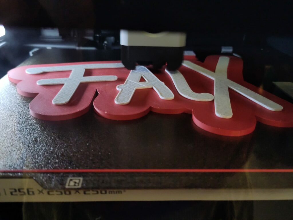 Zu sehen ist, wie der 3-D-Drucker den Schriftzug "FalX" druckt. Das ist der letzte Schritt, um zu illustrieren, wie ein 3-D-Druck entsteht.